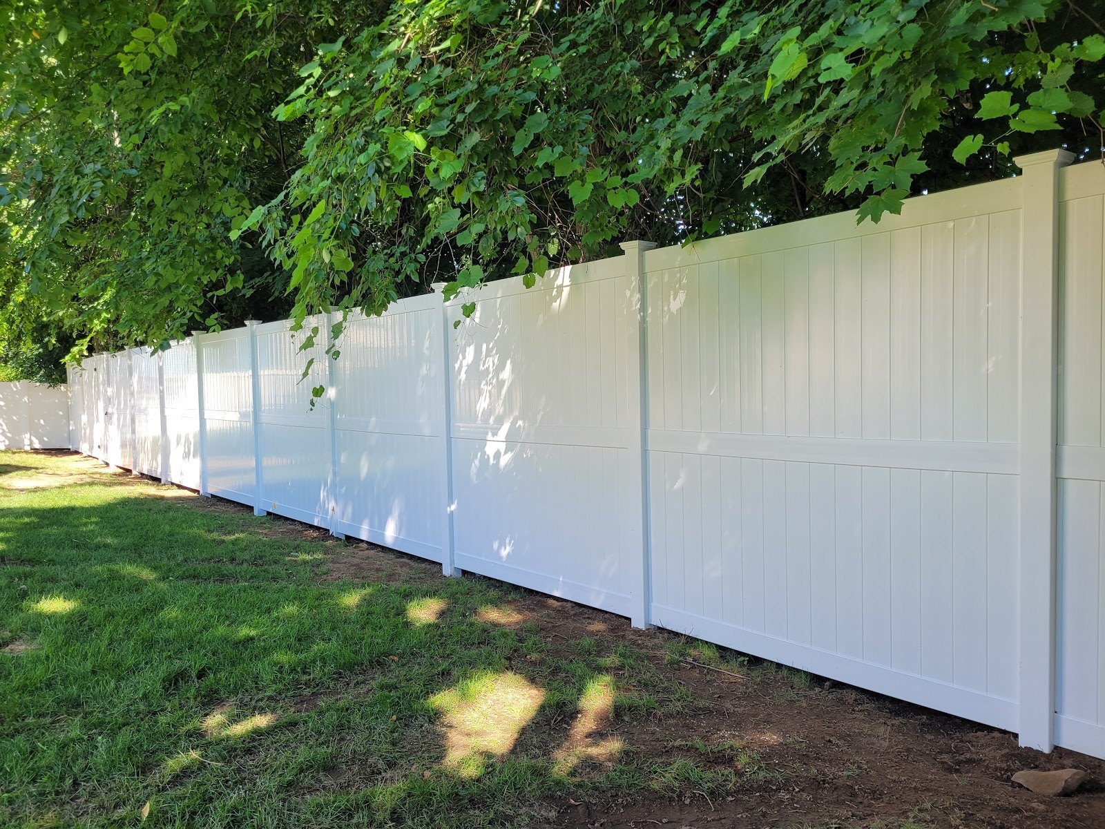 Long run of white vinyl privacy fence installed by Sullivan & Sons Fence